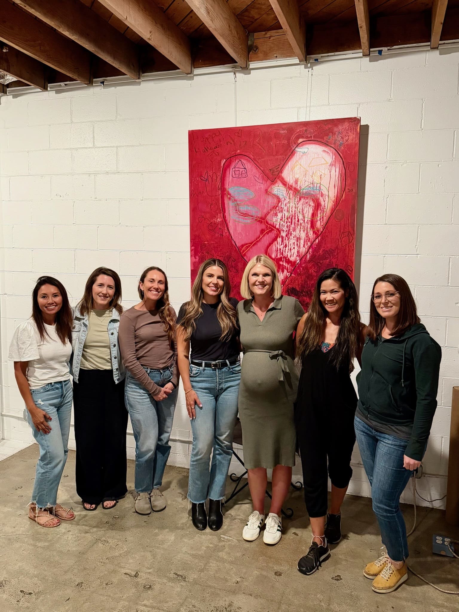 Women standing in a row, with arms around each other, supporting each other in growing their businesses.